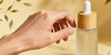 Hand applying clean skincare serum to face, emphasizing product texture and natural ingredients.